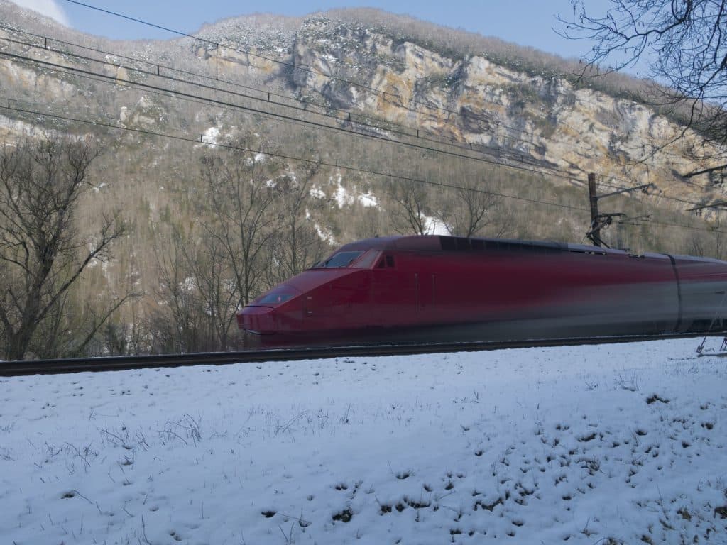a red and white train on a track in the snow